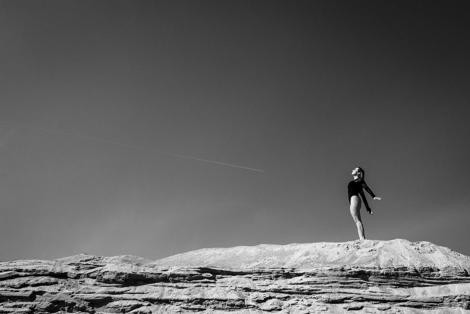 Beyond Determinism — A figure suspended above a bare ridge and an open sky. Photograph by Albert Pocej, On the Edge.
