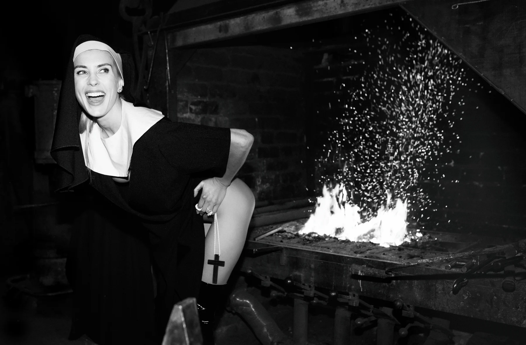 Confession — A nun’s habit, a raised hem and a smile beside the fire. Photograph by Albert Pocej, On the Edge.