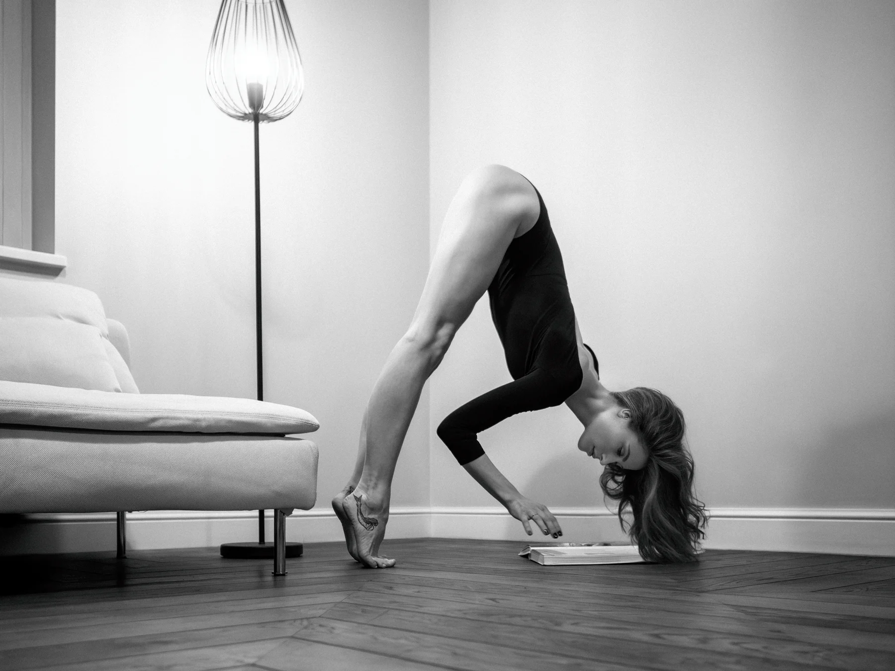 Dialectic Balance — An inverted pose interrupts the order of an armchair and a lamp. Photograph by Albert Pocej, Attachment Issues.