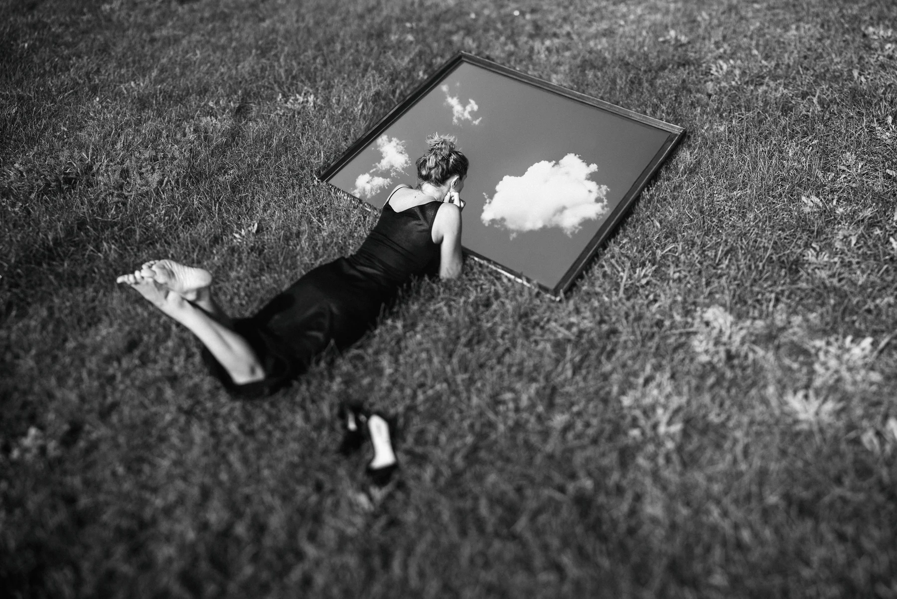 Internal Horizons — A mirror brings the sky down beside a figure lying in the grass. Photograph by Albert Pocej, Perfectly Normal.