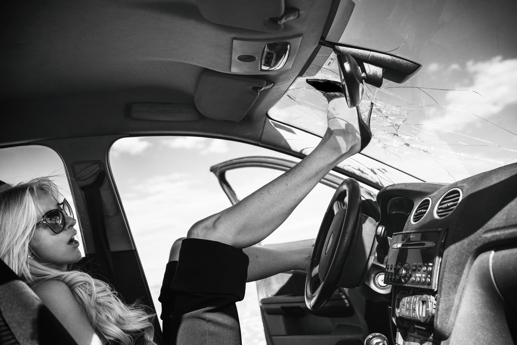 Louboutin Revenge — A high heel reaches the roof of a car from the passenger seat. Photograph by Albert Pocej, On the Edge.