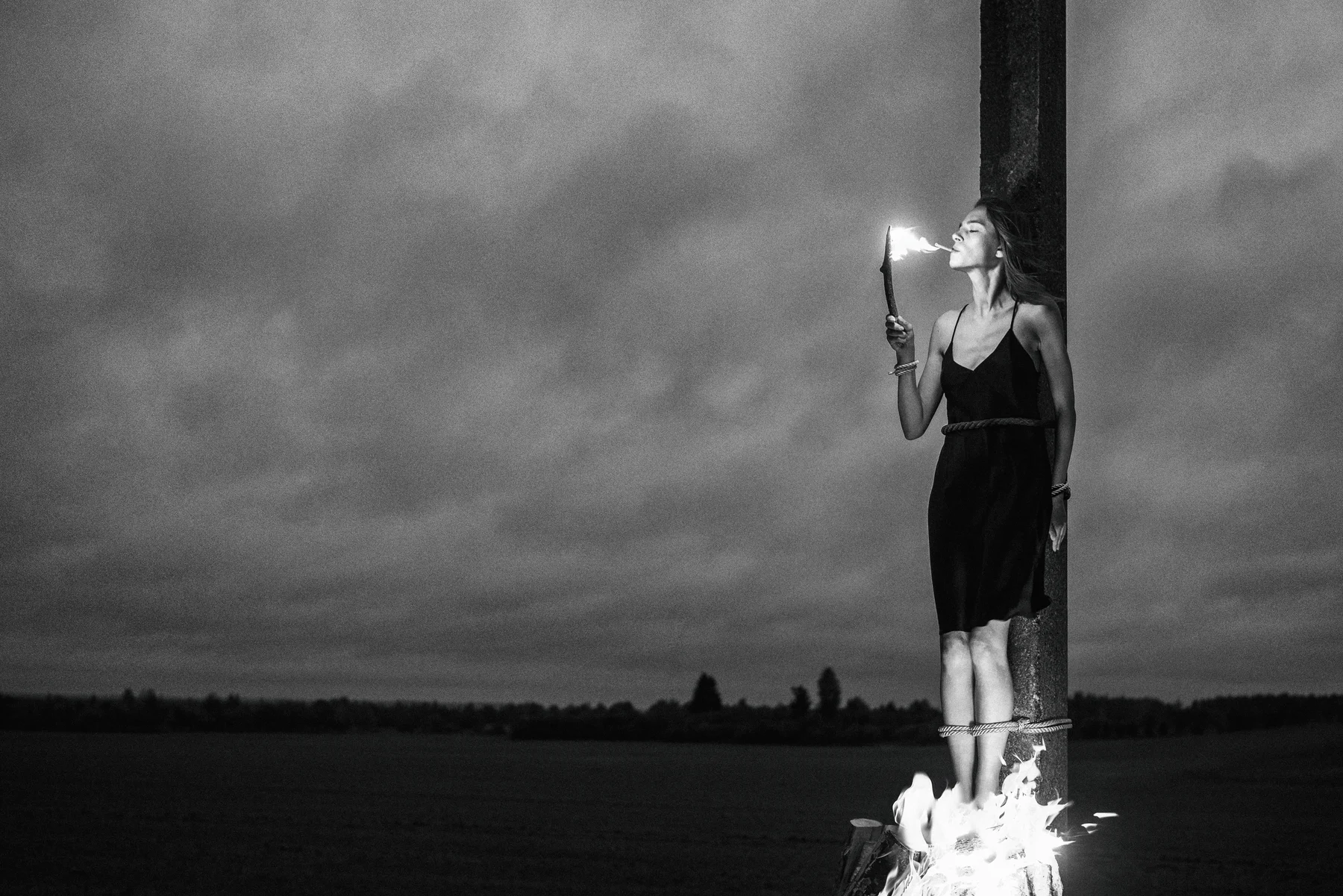 Malleus Maleficarum — A cigarette is lit while flames rise at the woman’s feet. Photograph by Albert Pocej, On the Edge.
