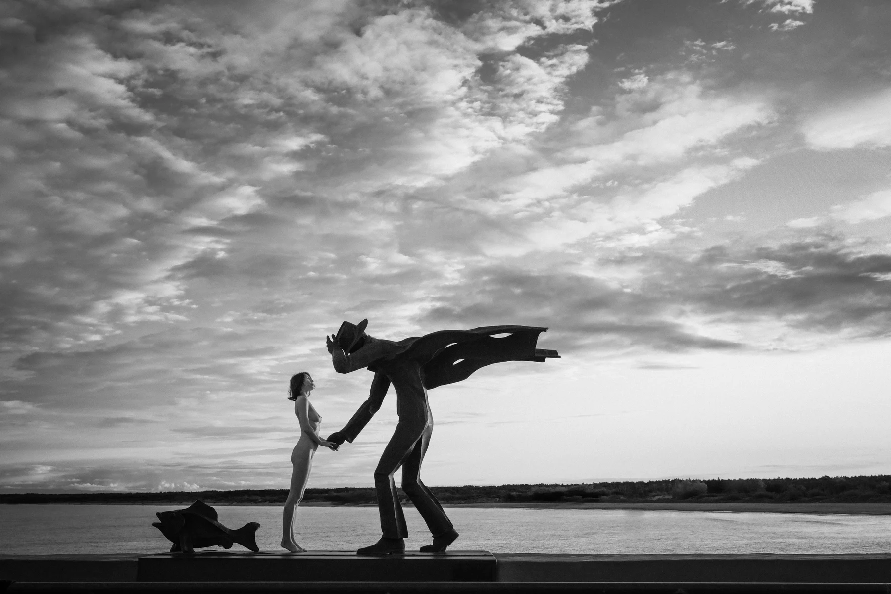 Monumental Love — A human gesture meets a much larger sculptural figure by the sea. Photograph by Albert Pocej, Attachment Issues.