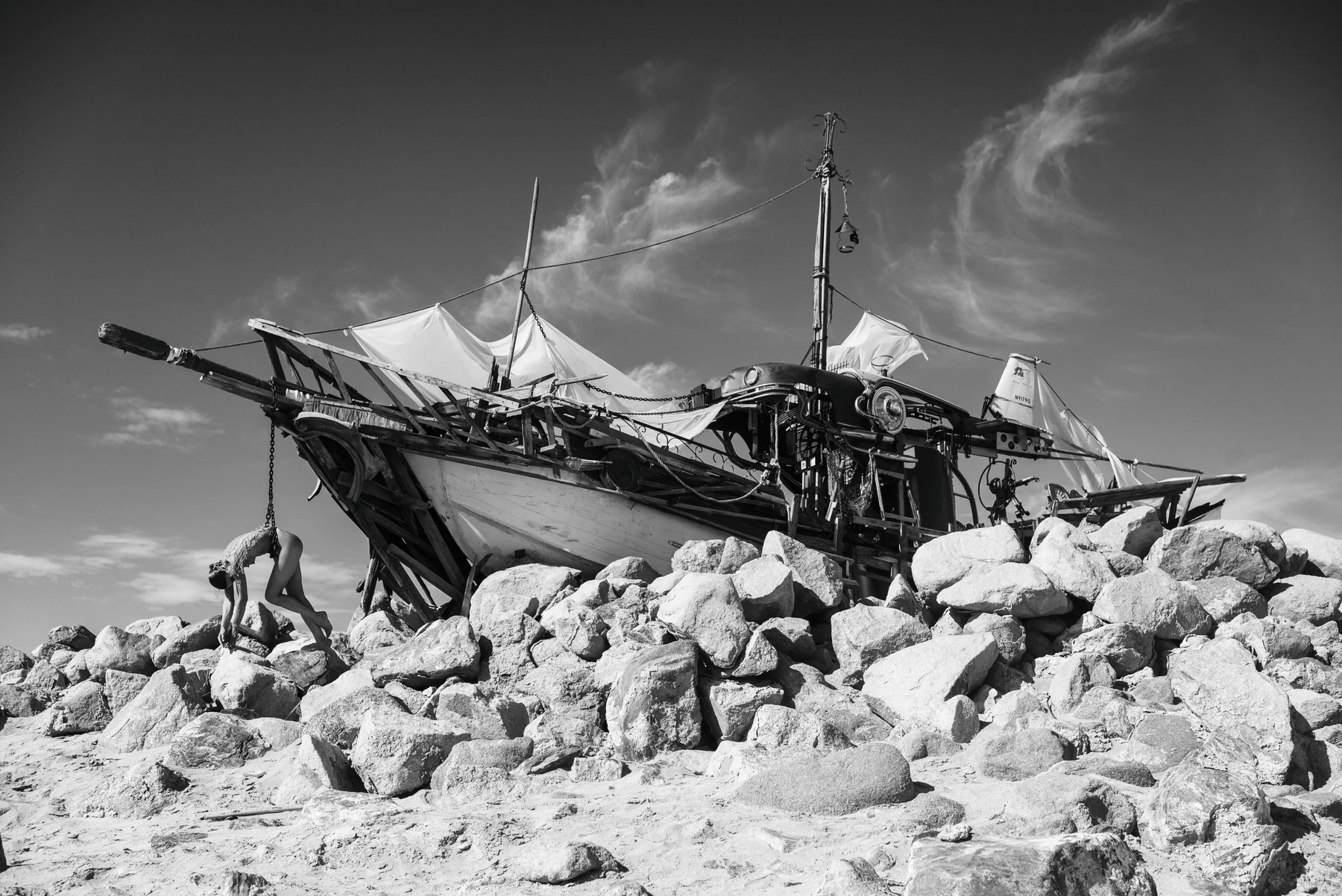 The Last Mermaid — A figure lies across a wrecked boat on a rocky shore. Photograph by Albert Pocej, California.