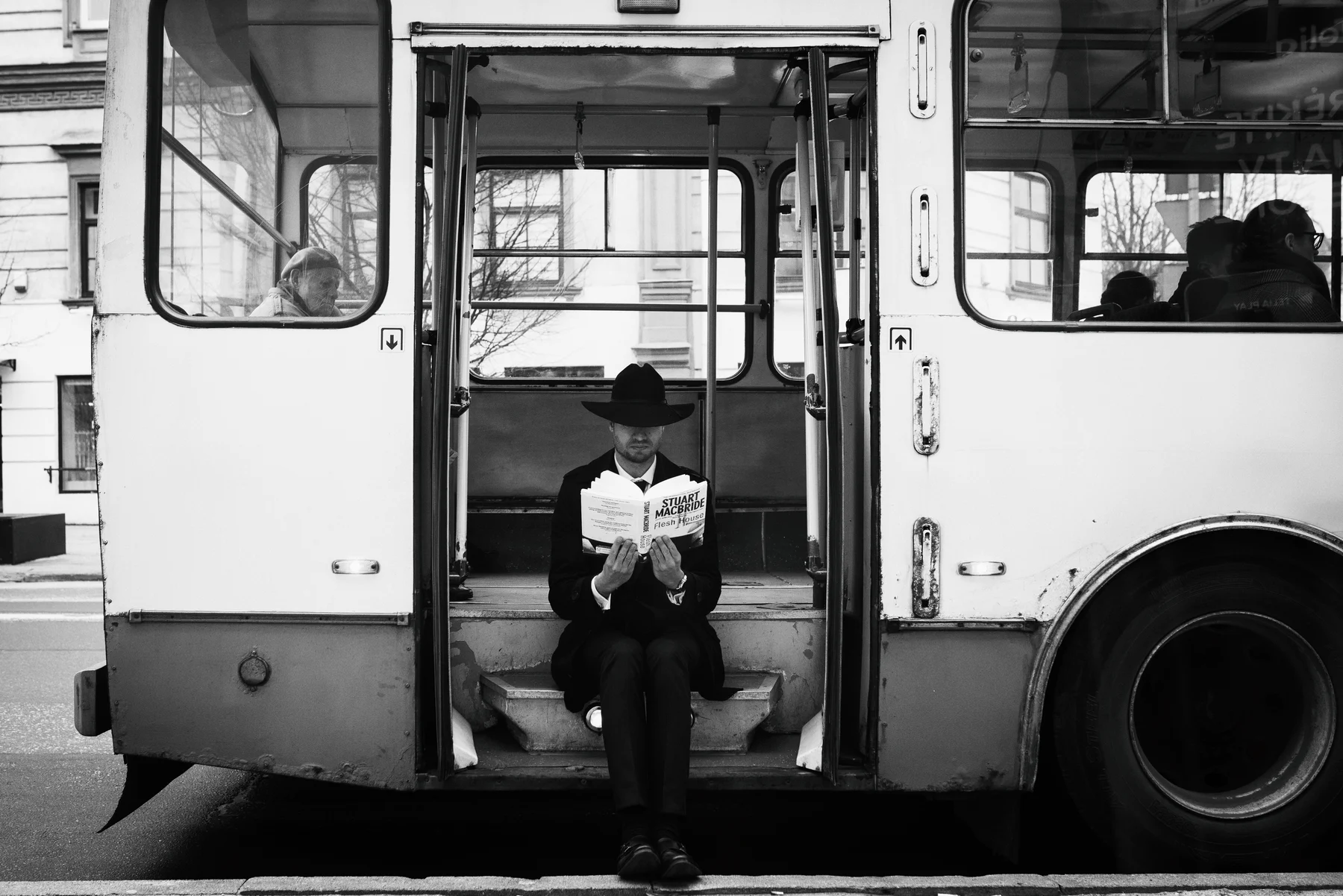 Ticket To Read — A reader pauses in the open doorway of a bus. Photograph by Albert Pocej, Perfectly Normal.