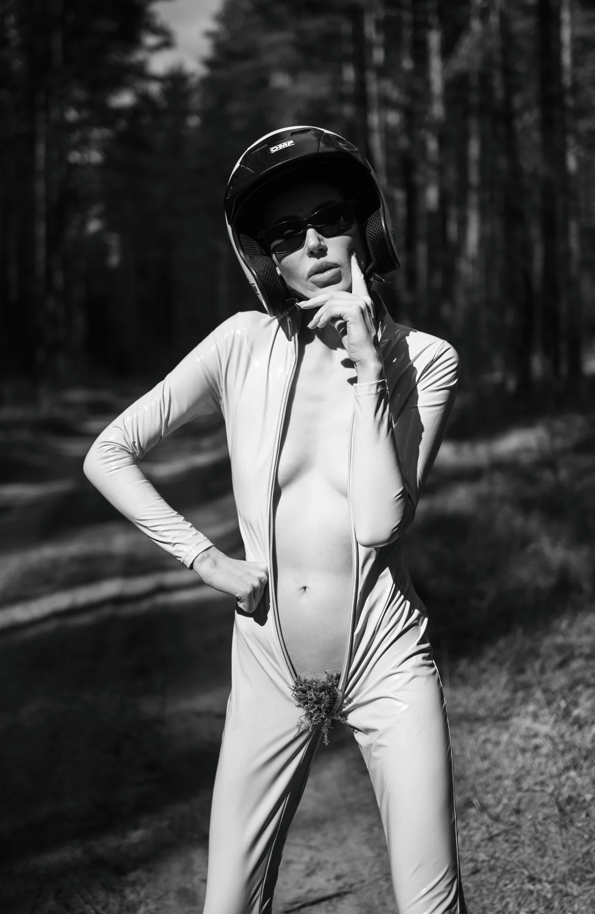 Unzipped Venus — An open racing suit, a helmet and a fragment of the forest. Photograph by Albert Pocej, On the Edge.