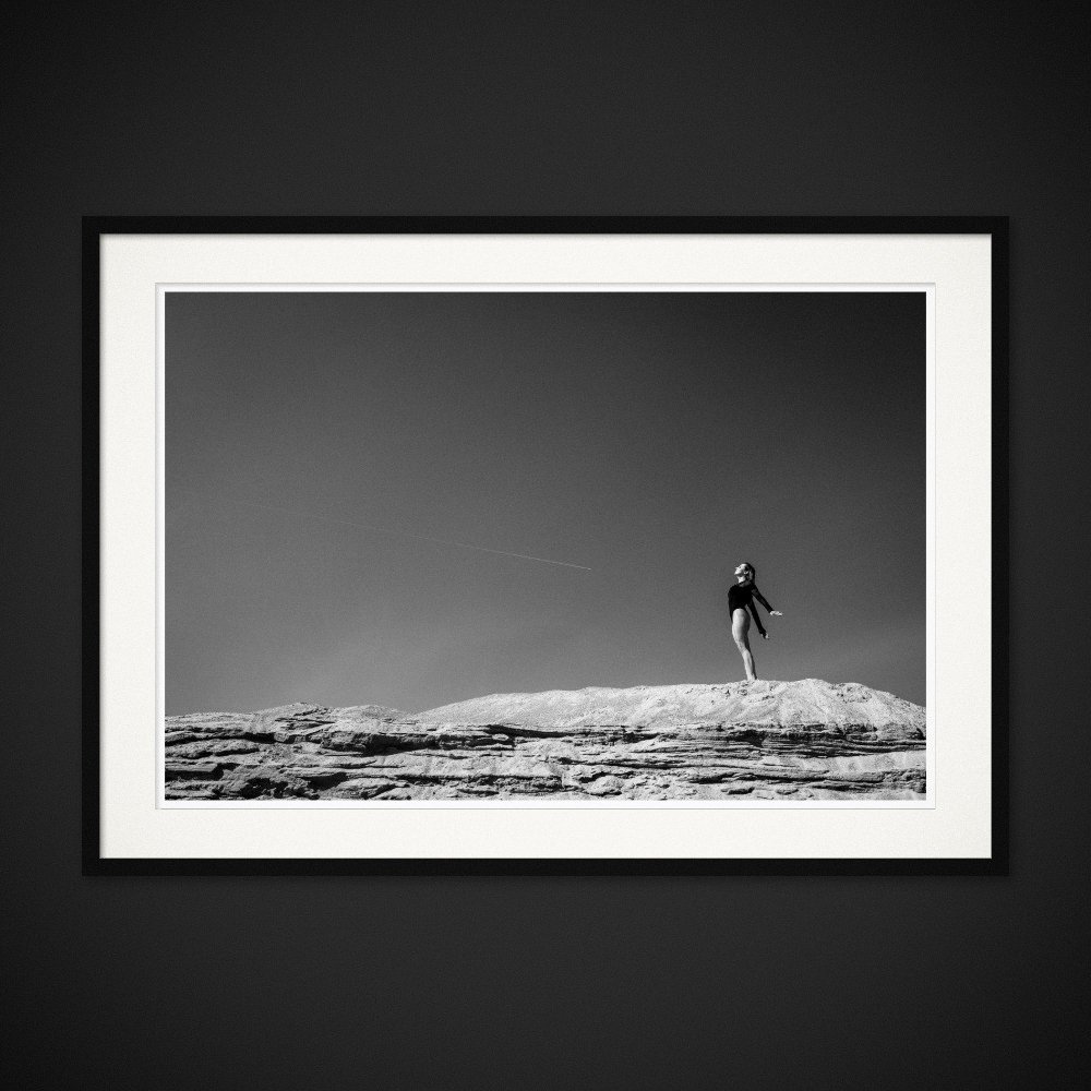 Beyond Determinism — A figure suspended above a bare ridge and an open sky. Framed edition by Albert Pocej.