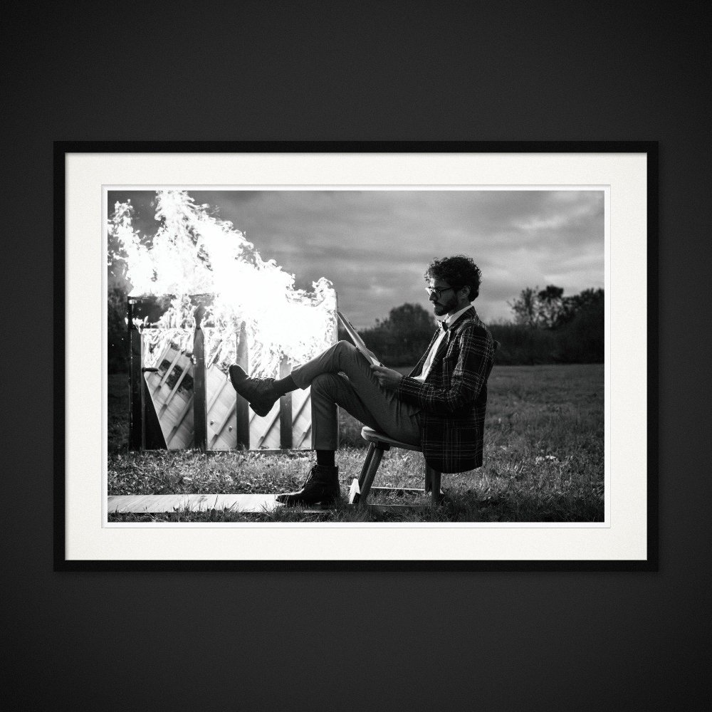 Fahrenheit 440 — A seated figure rests a foot against a burning piano. Framed edition by Albert Pocej.