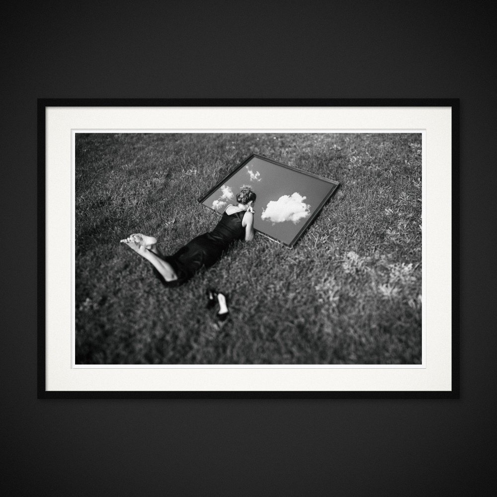 Internal Horizons — A mirror brings the sky down beside a figure lying in the grass. Framed edition by Albert Pocej.