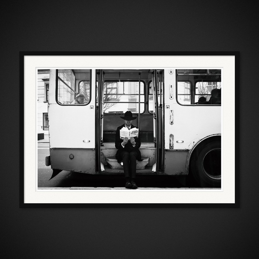 Ticket To Read — A reader pauses in the open doorway of a bus. Framed edition by Albert Pocej.