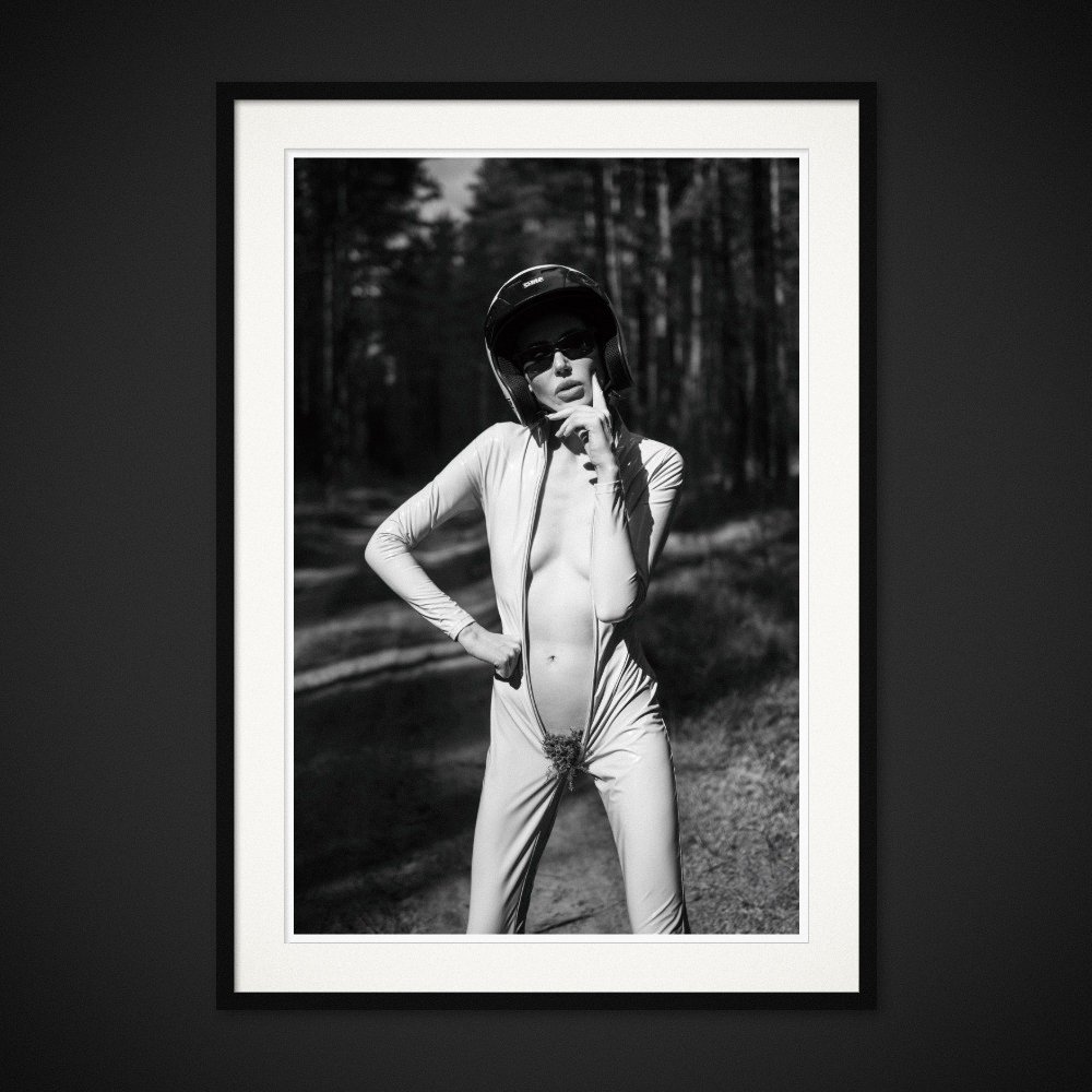Unzipped Venus — An open racing suit, a helmet and a fragment of the forest. Framed edition by Albert Pocej.